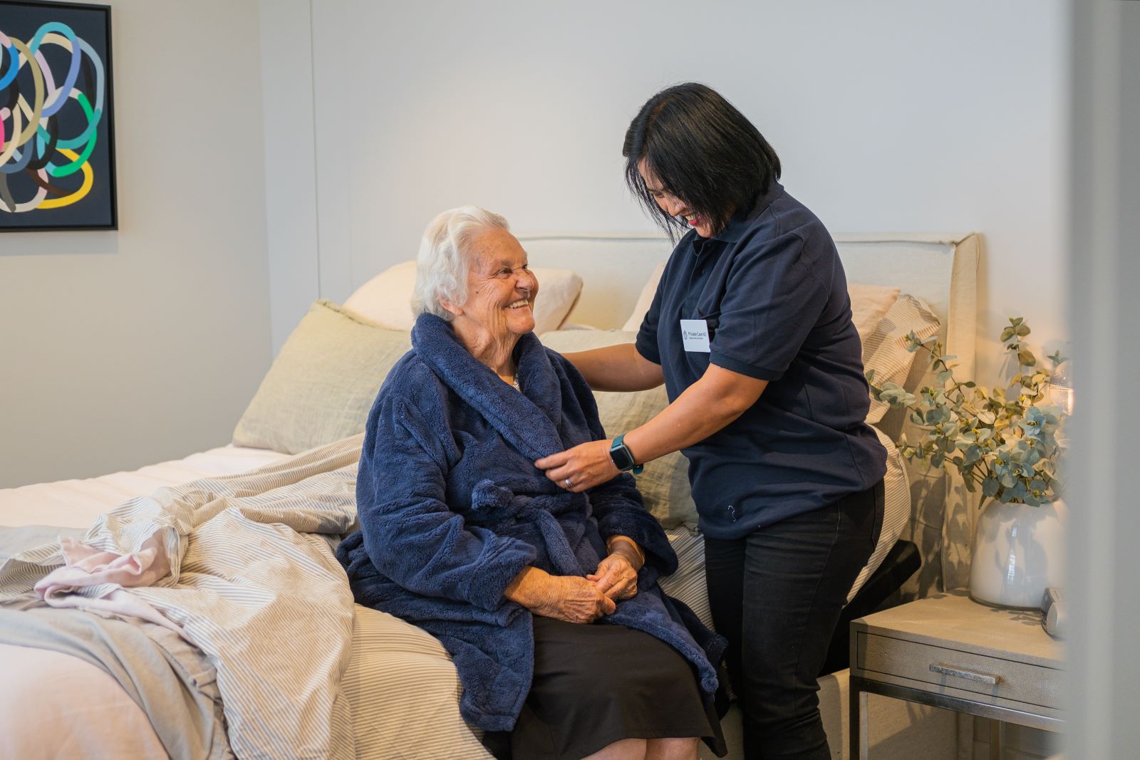 A caregiver helps an elderly woman with bedtime routines.