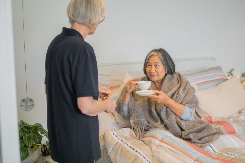 A support worker gives a senior woman a cup of tea.