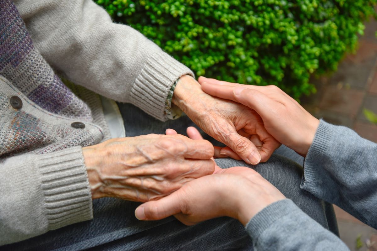 Young hands hold elderly hands.