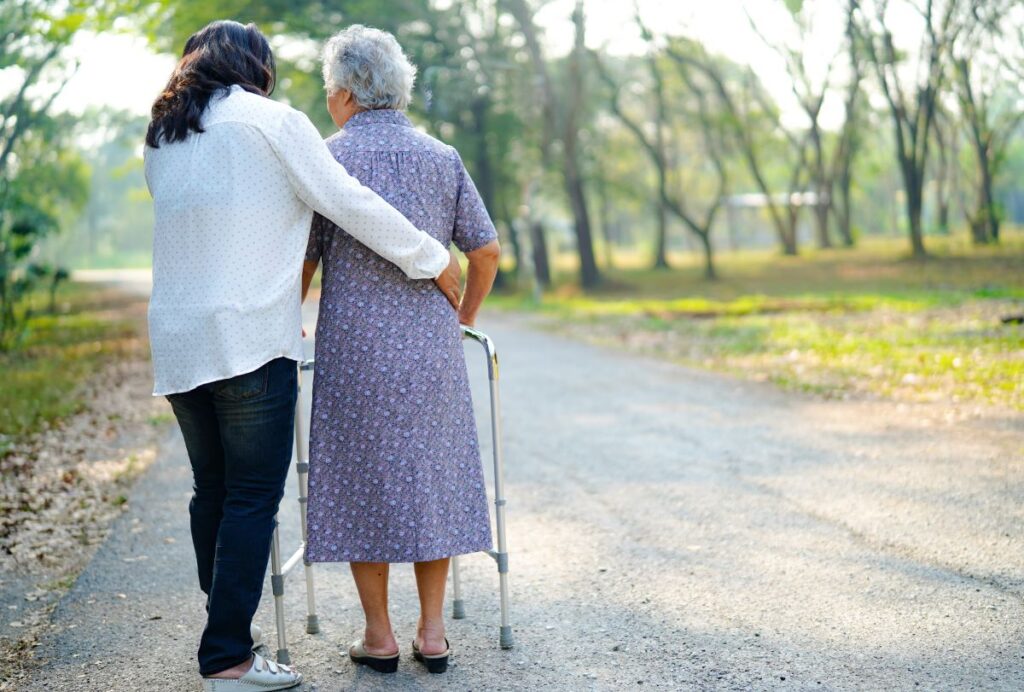A woman helps an elderly woman using a walker.