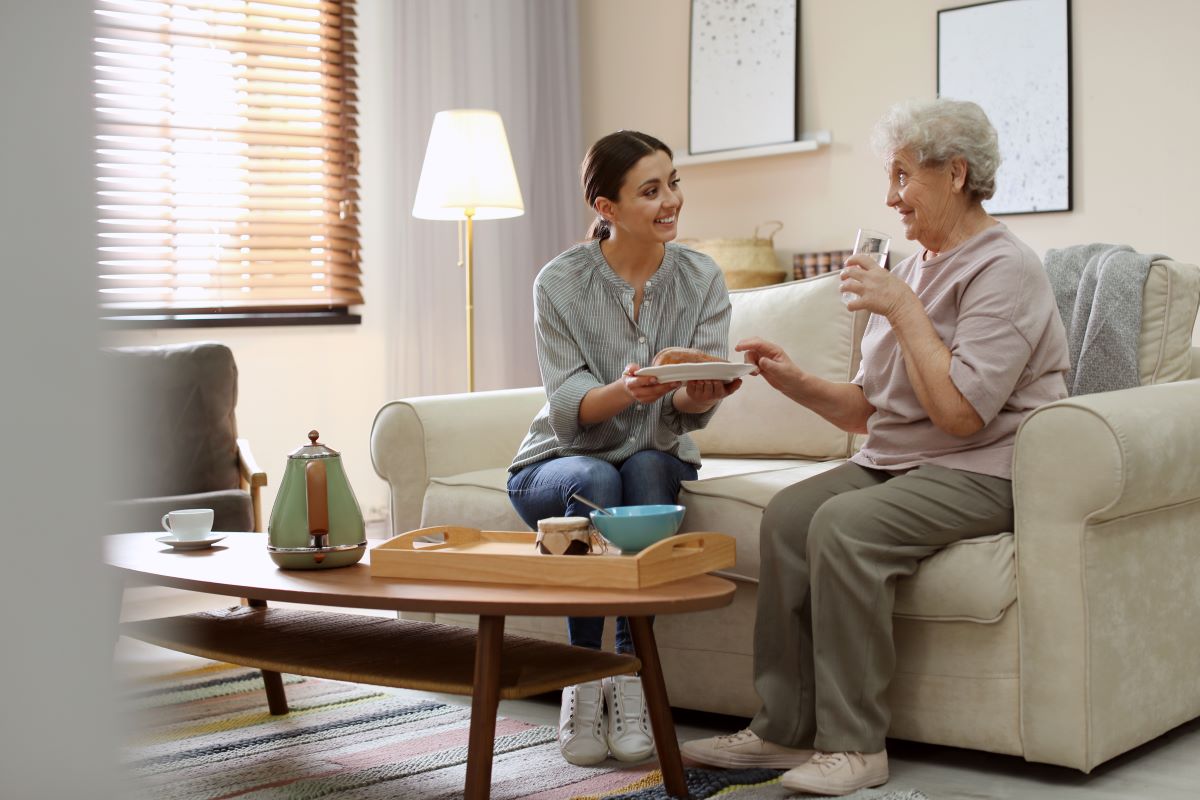 A carer serves an elderly woman.
