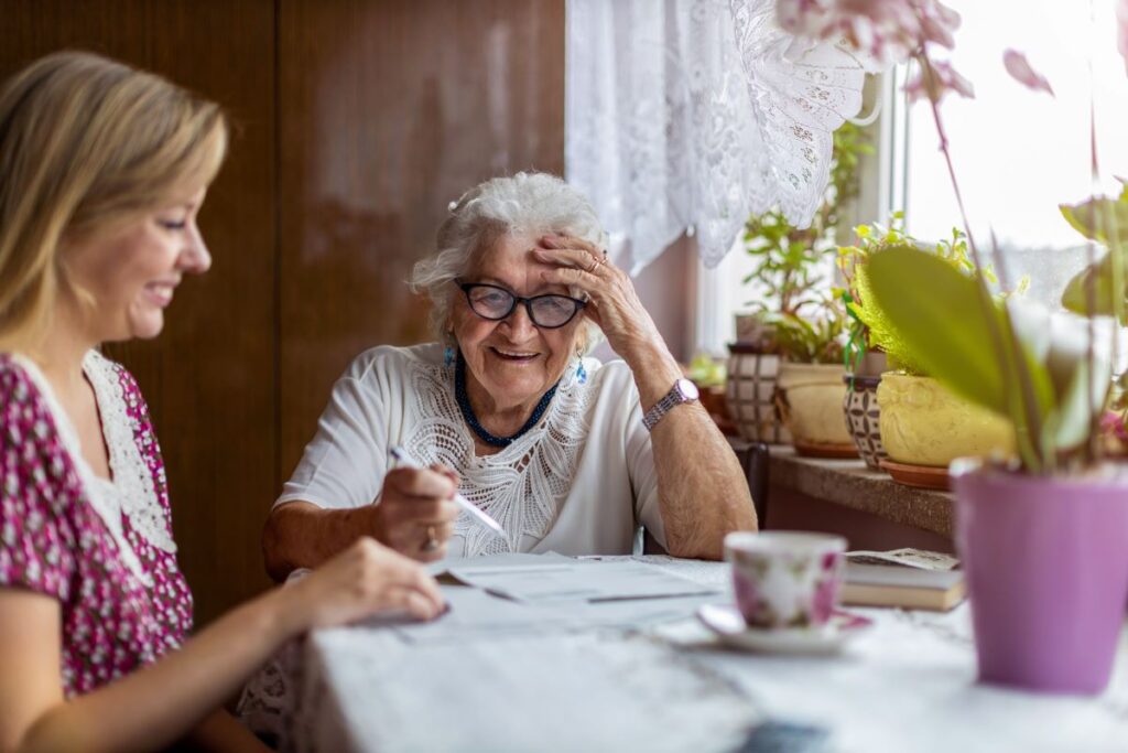 A carer sits with an elderly woman.