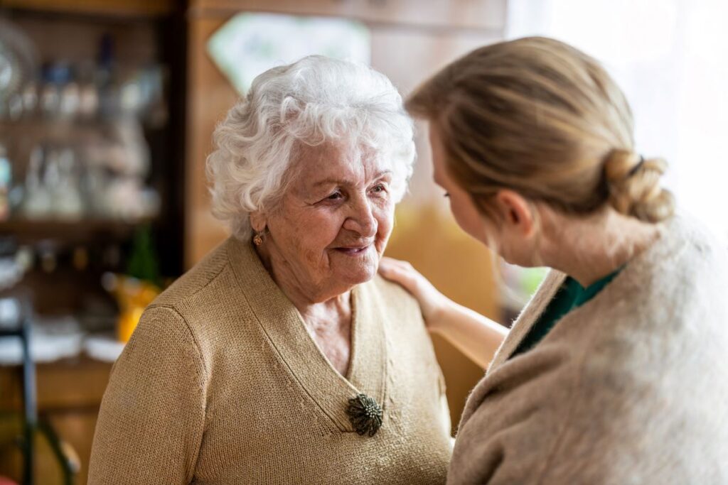 A carer checks in with an elderly woman.