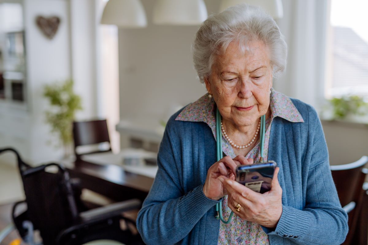 An elderly woman uses a smartphone at home.